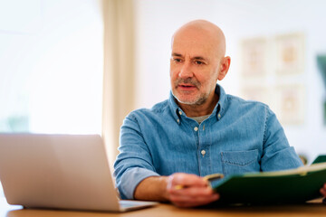 Confident mid aged man using laptop and having video call