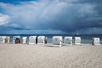 Sandy beach on the coast of the Baltic Sea in Strande / Kiel in Germany. With several beach chairs,...