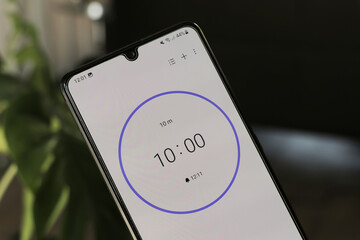 A phone with a black and white 10-minute timer to study with the pomodoro method on a blurry...