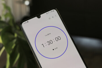 A phone with a black and white 1 hour and 30-minute timer to study with the pomodoro method on a blurry background