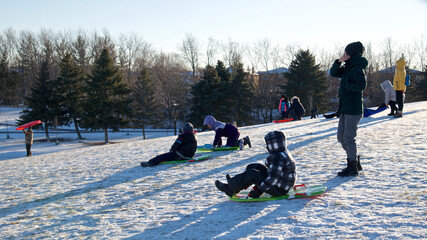 Toronto, Ontario / Canada - Jan 14, 2023:  Winter sport toboggan -  mother and son playing...