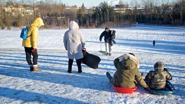 Toronto, Ontario / Canada - Jan 14, 2023: Family playing toboggan in winter.