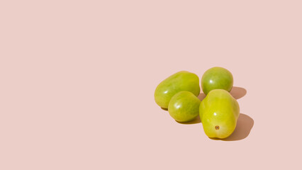 Green cherry tomato isolated on pink background with copy space, mockup