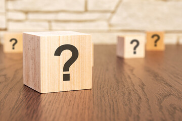 wooden blocks with question marks on wooden table, close up. space for text