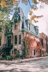 Obraz na płótnie Canvas Alley in Montreal in autumn showing an old historical building covered in plants that are turning red