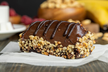 Fresh sweet cake with banana in chocolate glaze and milk filling