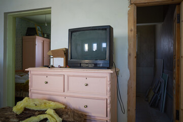 an old tube TV on a pink wooden chest of drawers in an apartment where construction and renovation is underway