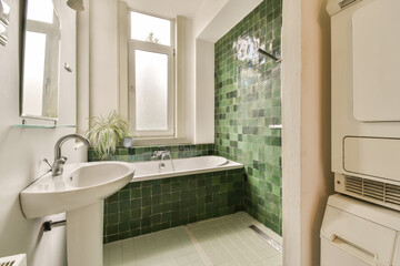 a bathroom with green tiles on the walls and white fixtures in the tub, toilet and sink are all visible