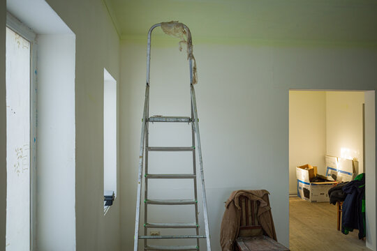 construction aluminum staircase on the background of plastered walls inside the house in which renovation is underway