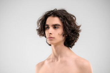 Portrait of a handsome young man with lush curly hair on a white background