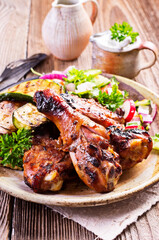 Traditional barbecue chicken drumsticks with grilled vegetable and lettuce served as close-up on a rustic design plate