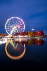 La Grande Roue de Montreal at night reflecting in the Saint Lawrence river with its lights on