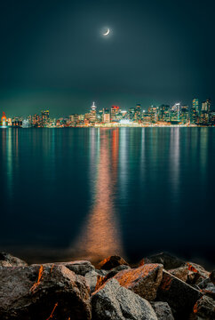 Cityscape of Vancouver at night as seen from North Vancouver sea shoreline