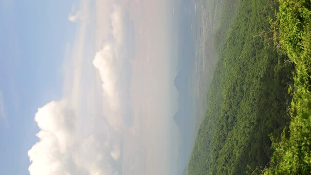 time lapse of a hilly area with trees and other hills in the background - clouds moving in the sky casting shadows