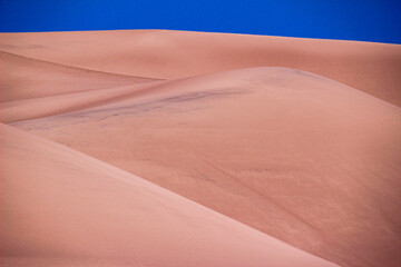 Abstract of flowing sand dunes with blue sky in Great Sand Dunes national park, Colorado. Background.
