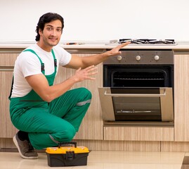 Young contractor repairing oven in kitchen