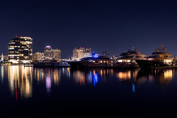 Fototapeta na wymiar Yachts docked in a marina at night in Palm Beach with the downtown West Palm Beach skyline in the background