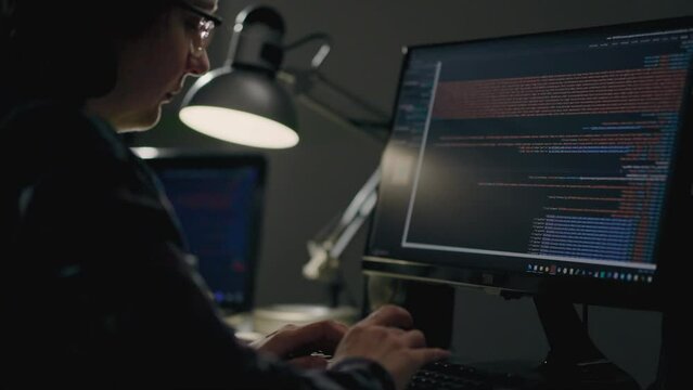 IT specialist girl works sits at a laptop computer monitor, writes artificial intelligence code while working at home outside the office. Woman programmer is involved in the design of a neural network