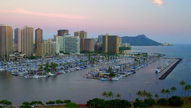 Aerial Shot Of Boats Moored At Harbor Near Buildings Against Sky, Drone Flying Forward Towards City At Dusk - Oahu, Hawaii