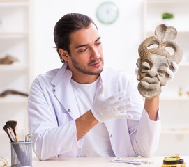 Young male archaeologist studying ancient african stonemask