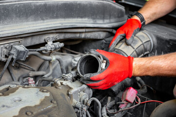 The car mechanic disconnected the air pipe from the car engine. Car repairs
