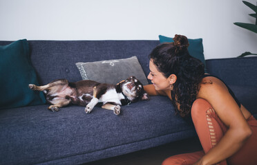 Caucasian woman 30s resting at home apartment spending time with best friend - lovely morgel doggie, female communicating with favourite cute pet enjoying friendship and feeling love in living room