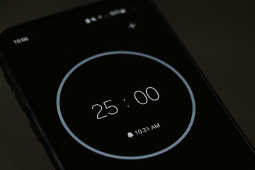 A phone with a black and white 25-minute timer to study with the pomodoro method on a blurry background