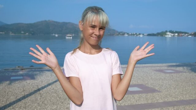 The teenager is confused. Young girl at a loss on the seashore.