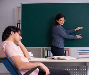 Old female teacher and male student in the classroom