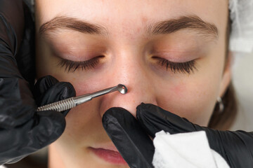 Mechanical facial cleansing with metal device at the beautician clinic. Cosmetology Professional procedure for cleansing pores and skin from defects Close-up 