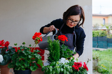dark hair woman watering potted plants outdoors