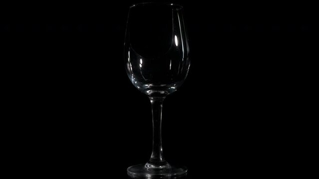 Lonely broken glass on black background. A view of abandoned broken wine glass spinning on the black background. A concept of love failure in people life.