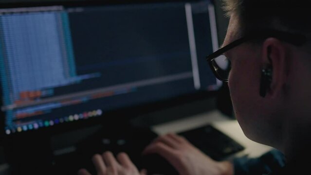 Remote part-time job, a young man actively works at home, the work of an IT specialist programmer, sits in front of a monitor, writes code for artificial intelligence. Building a new neural network
