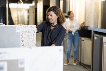 Handsome man choosing ceramic flooring for his home in hardware store