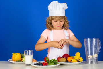 Child chef dressed cook baker apron and chef hat isolated on studio background. Healthy nutrition kids food.