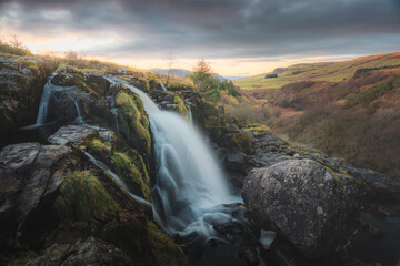Moody, dramatic landscape of Loup of Fintry waterfall at sunset in Stirlingshire, Scotland, UK.