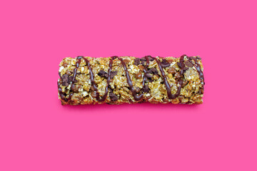 Muesli chocolate bar on a pink background. Healthy sweet dessert snack. Cereal muesli with chocolate and berries on a pink background. Carb bar for energy replenishment