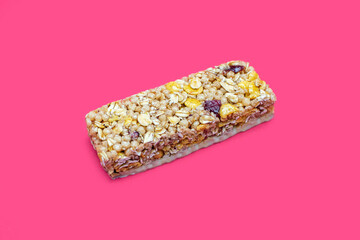 Muesli bar on a bright pink background in the center. Healthy sweet dessert snack. Cereal muesli with nuts, oatmeal and berries on a pink background. Delicious and healthy dessert