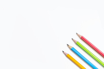 Four multi-colored pencils on a white background. Red, green, blue and yellow pencils. Free space for text. Pencils and empty space for text. The concept of learning or drawing