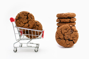 Chocolate chip cookies lie in a cart on a white isolated background. Chocolate sweet cookie in a mini toy cart as a concept for buying, selling and delivering goods