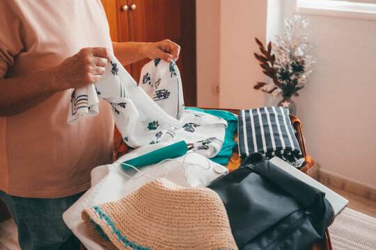 Senior Woman Packing Her Stuff Into A Suitcase Preparing For Vacation Trip. Elderly Woman Checking Her Luggage On The Bed At Home Before To Leave