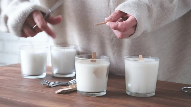 creative occupation of making candles, unrecognizable woman cutting the wooden wick