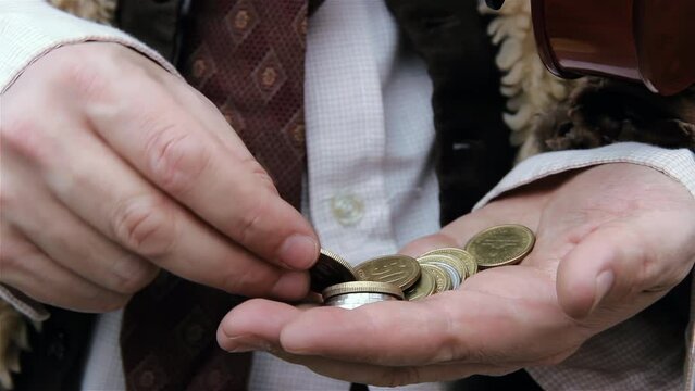 Hands of a Beggar in the Street Holding a Few Coins and Bills While Sitting on a Bench in Buenos Aires, Argentina. Close Up. 4K Resolution.