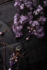 author collection jewelry with lilac gemstones, crystals  and pearls demonstrated at black stones background.  fashion and jewelry concept. flat lay