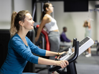 Fototapeta premium Caucasian woman training on exercise bike in gym