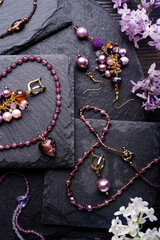 author collection jewelry with lilac gemstones, crystals   demonstrated at black stones background.  fashion and jewelry concept. flat lay.