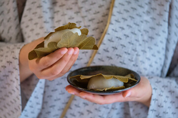 Hands holding japanese Kashiwa mochi. Japanese mochi with red bean paste filling wrapped with an...