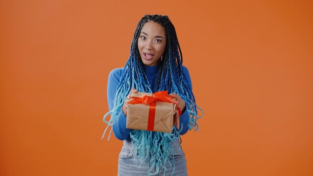 Cheerful African American woman gives gift box with red bow