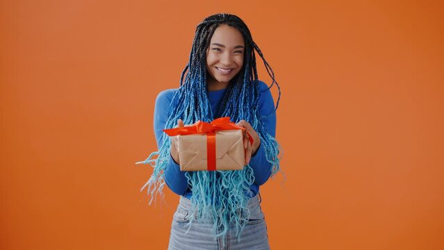 Generous young woman smiles and nods offering to take gift