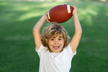 American style football. Kid boy having fun and playing american football on green grass park.